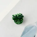 Makro-Detail einer dunkelgrünen Haarklammer aus Acetat mit Marmortextur auf redaktionellem Hintergrund - Grünes Blumenmuster