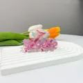 Detalle de pinza para el pelo con lazos rosas y perlas sobre soporte de piedra - Lazo Rosa