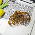 Grande molletta per capelli leopardata per capelli folti appoggiata su un laptop - 11cm / Leopardo Caramello