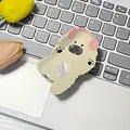 Supporto per telefono cucciolo bianco riccio con cuffie rosa su una tastiera - Cane con Cuffie Rosa