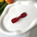 Elegant deep red acetate bow hair claw clip on a white decorative ceramic tray - Red