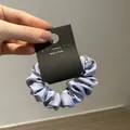 Dettaglio di un elastico per capelli in raso lavanda con una texture setosa e lucida - Blu viola