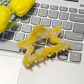 Sternförmige Haarklammer aus Acetat in Gelb-Marmor-Optik auf einem Laptop mit Tulpen - Oranger Stern