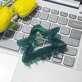 Dunkelgrüne sternförmige Haarklammer aus Acetat auf einer Laptop-Tastatur platziert - Dunkelgrüner Stern