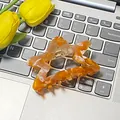 Haarklammer in Sternform mit bernsteinfarbener Acetat-Textur auf einer Laptoptastatur - Stern Orange