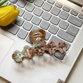 Elegant taupe tortoiseshell flower claw clip displayed on a laptop keyboard background - Green Coffee Floral