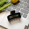 Classic matte black rectangular hair claw clip with golden metal accents on a laptop - Black 6cm