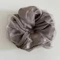 Detail view of a silver-grey organza mesh scrunchie with soft pleats and a silky sheen finish - Grey Brown