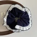 Detail of navy blue oversized scrunchie with white ruffle trim on a wooden tray - 13cm / Solid Navy Blue