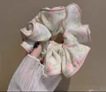 Gros plan d'un chouchou en tissu à fleurs roses avec des bords arrondis doux - Blanc Fleuri
