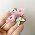 Vue détaillée de la pince à cheveux en acétate avec des ailes roses et un motif fantôme - Style Fantôme Papillon Décalé