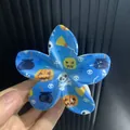 Détail d'une pince à cheveux fleur bleue avec motifs citrouilles et squelettes - Lettre E / ABS