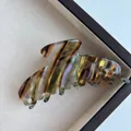 Macro di una grande clip per capelli in acetato con trama marmorea marrone e strisce cangianti - A Righe Cangianti Tabacco