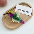 Macro detail of colorful hummingbird hair claw clip showing vibrant marble texture - Teal