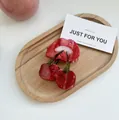 Detail view of a translucent red cherry hair claw clip with green leaf on wood - Lip Cherry