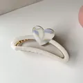Detail of a crescent-shaped hair claw with pearly texture and marble heart accent - Blue & White