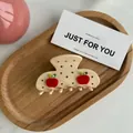 Détail d'une pince à cheveux en acétate crème avec motif pomme et strass sur plateau - Décoration Pomme Rouge / Pomme Beige