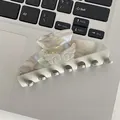 Creamy white acetate hair claw clip with wing relief and rhinestones on a keyboard - Marble Gray Wings