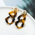 Macro detail of tortoiseshell acrylic rings linked with a polished gold oval metal stud - Beige Tortoiseshell Texture Style (EH00161)