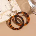Detailed view of tortoiseshell resin hoop earrings on a marble stone surface - Coffee Tortoiseshell Big Hoop (EH00087)