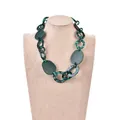 Collier en acrylique vert foncé avec anneaux marbrés présenté sur un présentoir - Acétate Vert