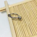 Detailed view of silver-plated spring clip earrings converter on a natural bamboo mat - White Gold
