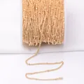 Close-up of 14k gold-filled DIY jewelry chain with small beads on a white spool - 14K Gold Plated