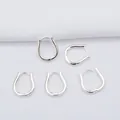 Polished 14k gold-plated U-shaped hoop earrings on white textured fabric background - Silver