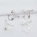 Close-up of four silver screw-on earring converters with DIY loops on white fabric - Silver