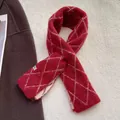 Détail macro d'une écharpe en maille bordeaux à motifs losanges avec étiquette tissée - Losange