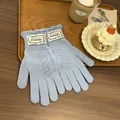 Detail of light blue knit gloves with ruffled cuffs and hollow diamond pattern on a table - Azure Blue
