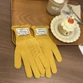Detail of yellow knit lace gloves with ruffled cuffs and label on a wooden tray - Yellow