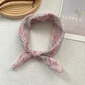 Floral chiffon silk scarf with pink flower pattern tied in a bow on a plush background - Girl Pink