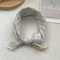 Detail of pink and green plaid square scarf tied in a stylish knot on soft fabric - Yellow Plaid