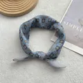 Close-up of sky blue geometric print silk scarf tied in a knot on textured background - Business Blue