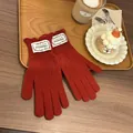 Close-up of dark red knit gloves with delicate hollow lace patterns on a wooden table - Red