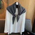 Dettaglio dello scialle di lana grigio scuro con bordi smerlati su una maglia bianca - Solo Scialle / Grigio