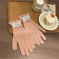 Detailed view of pink knitted gloves featuring elegant ruffle cuffs and woven brand labels - Pink