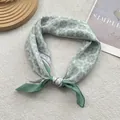 Dettaglio di un foulard in seta retrò con motivi geometrici in verde chiaro e viola - Verde