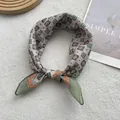 Détail d'un foulard en soie noué en boucle avec motif floral géométrique rétro - Vert