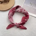 Detail of red floral cotton linen scarf featuring white flower patterns and rolled edges - Red