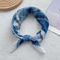 Dettaglio di un foulard blu e bianco con motivo geometrico annodato ad anello - 58 cm x 58 cm / Blu