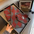 Detail of a red and grey argyle wool scarf folded in a tray with stylish accessories - Red