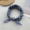 Detail of floral linen neck scarf with blue print and neat hemmed edges on wooden tray - Blue