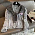 Close-up of gray knit cardigan with wool texture and pink decorative patch on a leather sofa - Gray