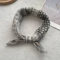 Detail of vintage patchwork silk scarf tied in a loop on a minimalist white background - Grey Green