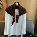 Détail d'un châle en laine marron avec bordures festonnées blanches sur t-shirt blanc - Châle Seul / Café