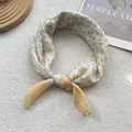 Detailed view of floral cotton linen scarf tied in a knot on a cozy white textured background - Small Flower Yellow