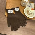 Close-up of brown knit gloves with hollow patterns and vintage floral label on wood tray - Coffee