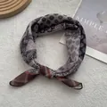 Dettaglio di una sciarpa vintage in lino con motivi paisley e geometrici su fondo ruvido - Nero